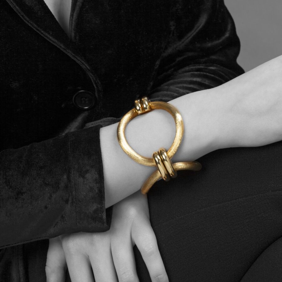 An eighteen carat yellow gold bracelet comprising three large circular curved links with satiné finish. Signed Cartier, made ca 1960 and numbered.