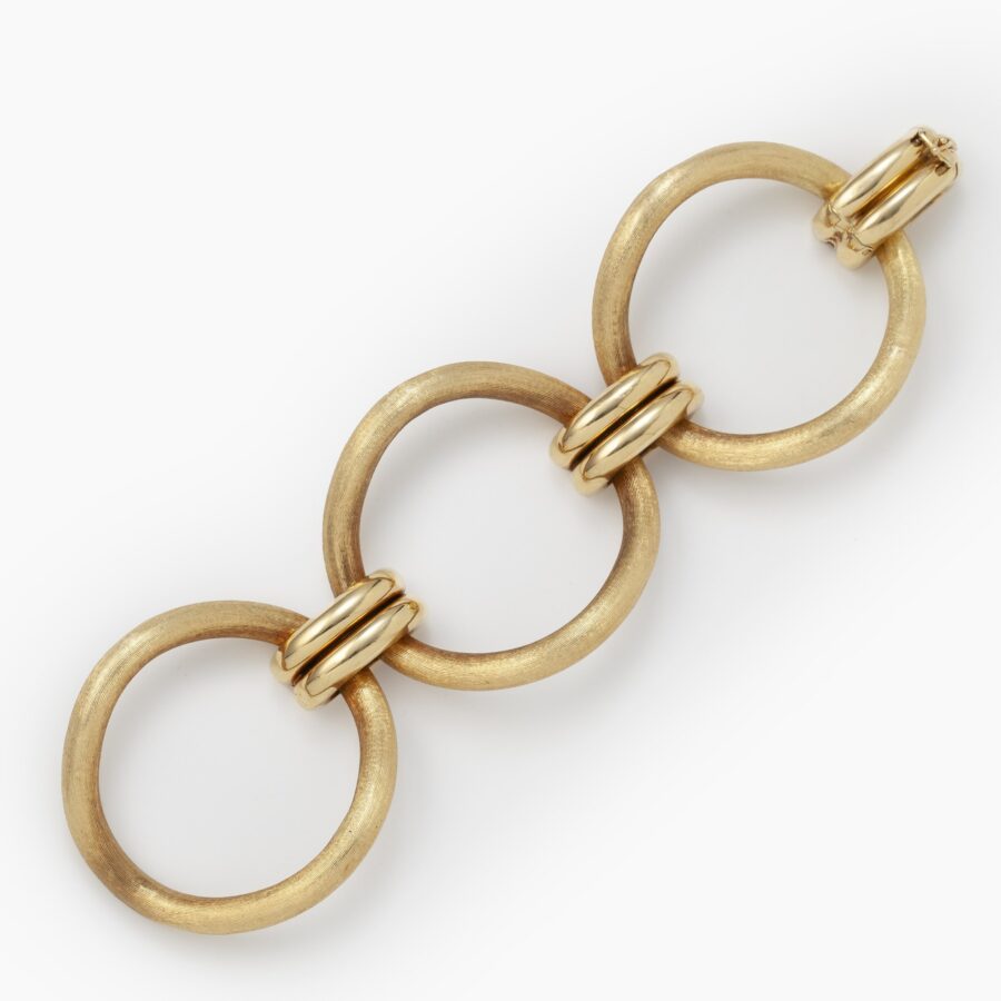 An eighteen carat yellow gold bracelet comprising three large circular curved links with satiné finish. Signed Cartier, made ca 1960 and numbered.