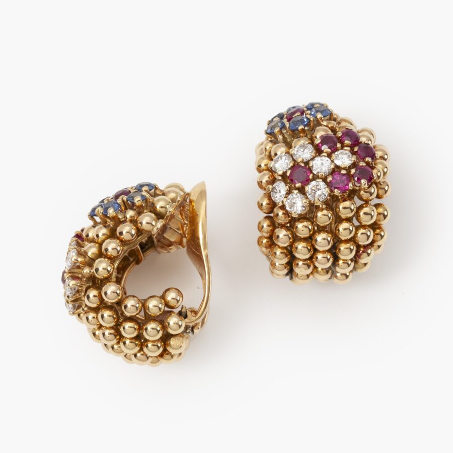 A pair of eighteen carat gold earclips model ‘Pelouse Hawaii’, set with diamonds, rubies and sapphires. Signed Van Cleef & Arpels, made ca 1950.