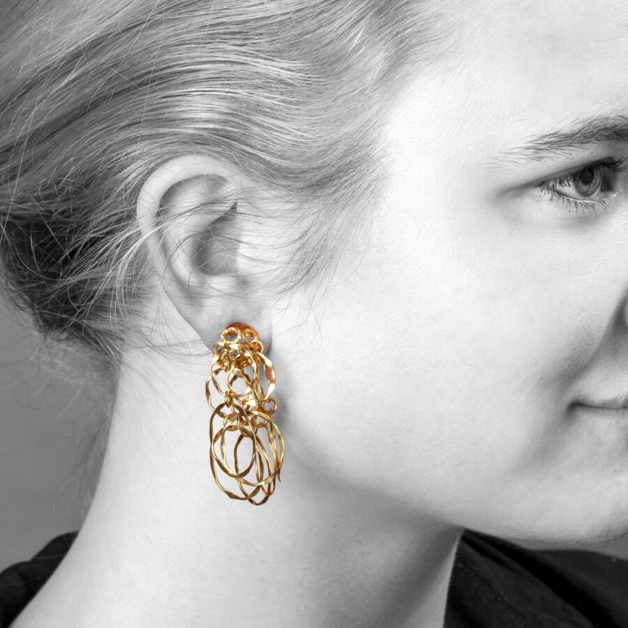 A pair of eighteen carat yellow gold earrings designed as a flowerhead clip on the ear, from which suspend many rings. Signed Cartier, made ca 1970.