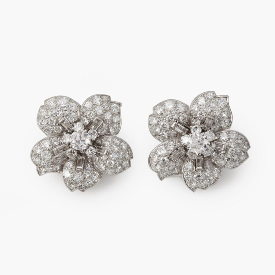 A pair of platinum clip earrings, each designed as a flower set with differently cut diamonds. Signed Cartier, made in London, ca 1950. In original case.