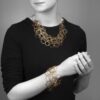 An eighteen carat yellow gold necklace with matching bracelet consisting of many strings of irregular round links. Signed Cartier, numbered. Made ca 1980.