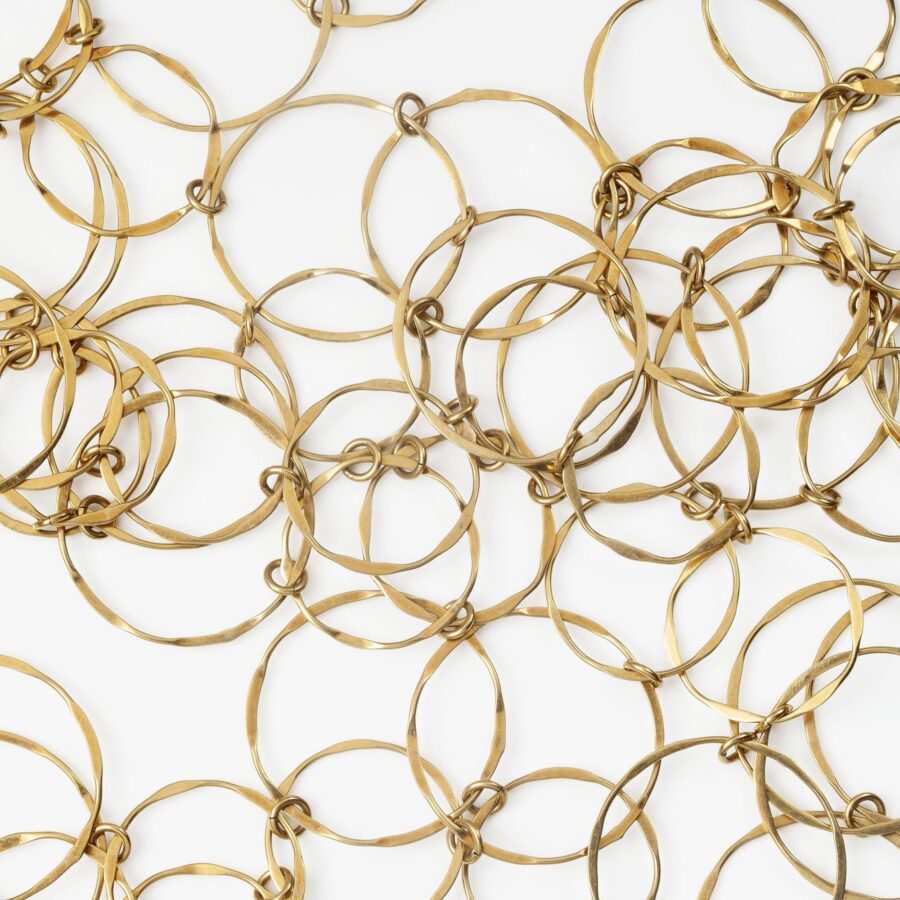 An eighteen carat yellow gold necklace with matching bracelet consisting of many strings of irregular round links. Signed Cartier, numbered. Made ca 1980.