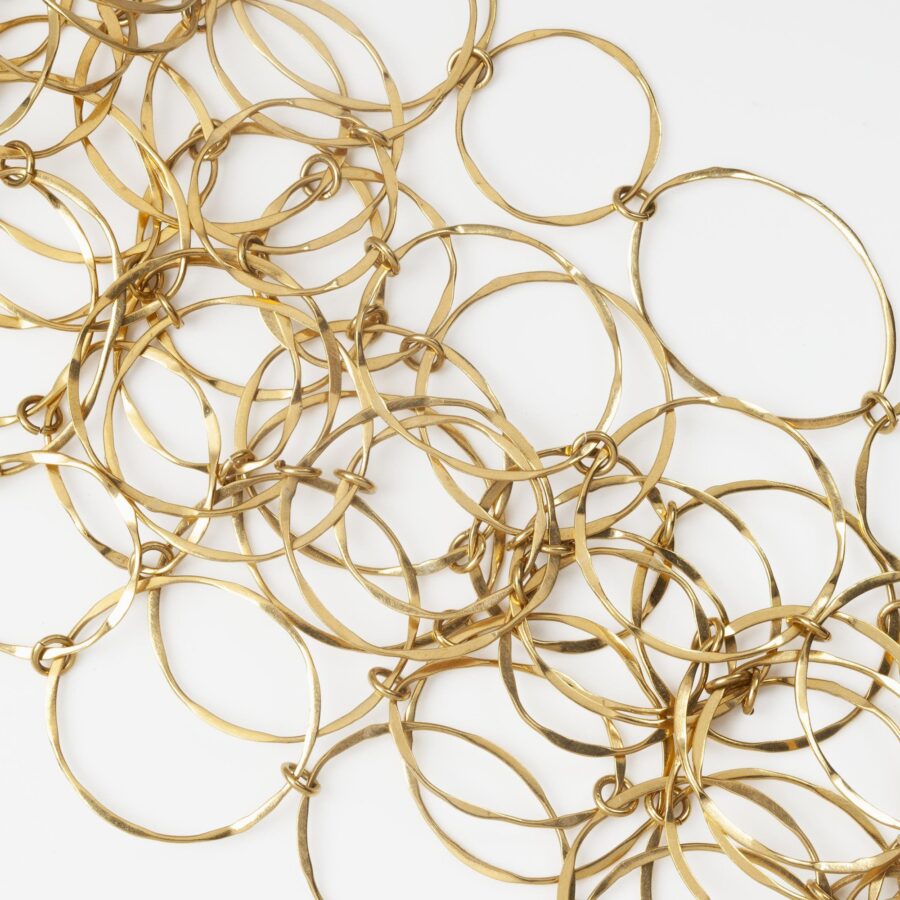 An eighteen carat yellow gold necklace with matching bracelet consisting of many strings of irregular round links. Signed Cartier, numbered. Made ca 1980.