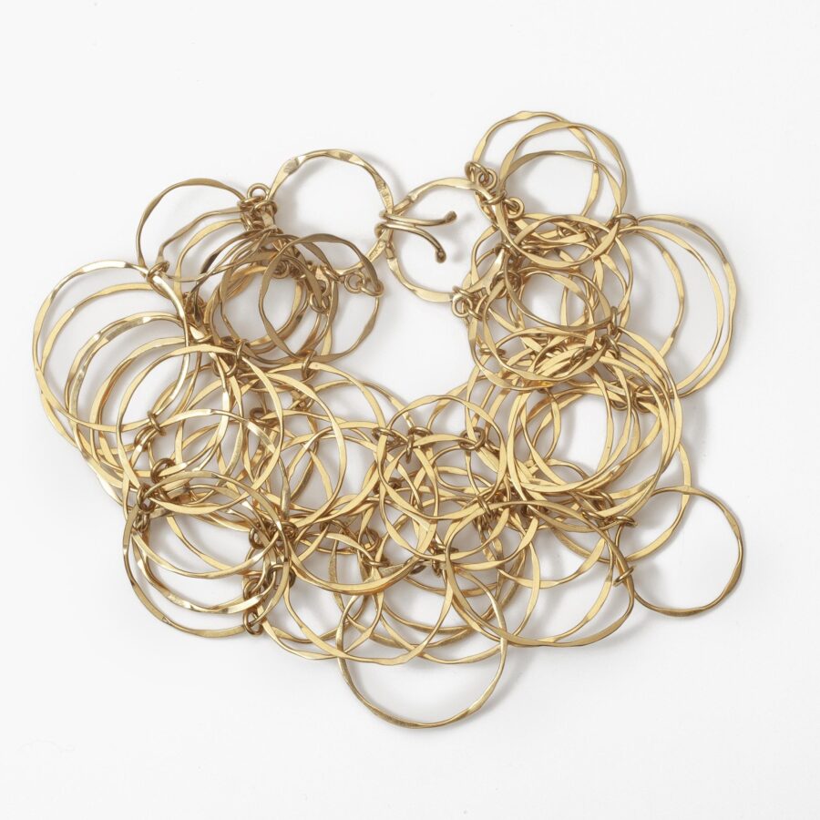 An eighteen carat yellow gold necklace with matching bracelet consisting of many strings of irregular round links. Signed Cartier, numbered. Made ca 1980.