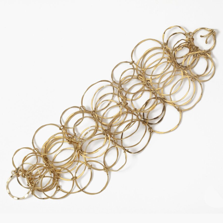 An eighteen carat yellow gold necklace with matching bracelet consisting of many strings of irregular round links. Signed Cartier, numbered. Made ca 1980.