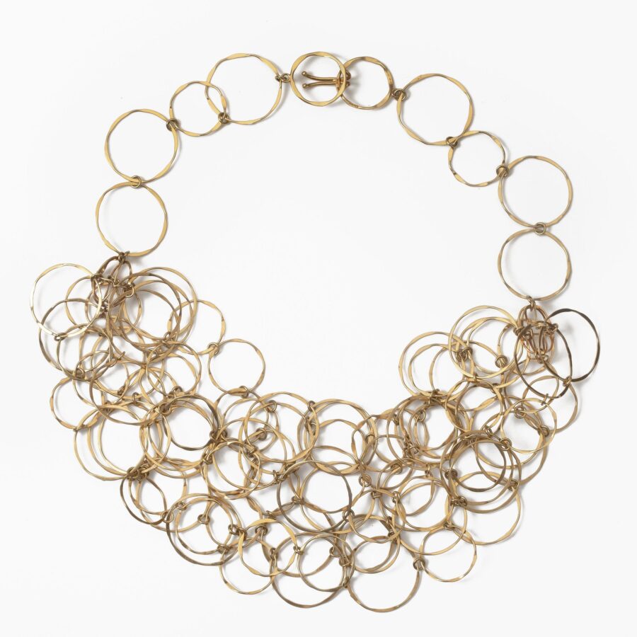 An eighteen carat yellow gold necklace with matching bracelet consisting of many strings of irregular round links. Signed Cartier, numbered. Made ca 1980.
