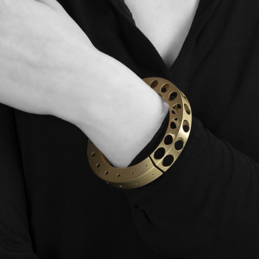 A fourteen carat yellow gold bangle 'Bracelet with Holes', signed Gijs Bakker, Amsterdam. Designed in 1992, part of the ‘Holes Project’.