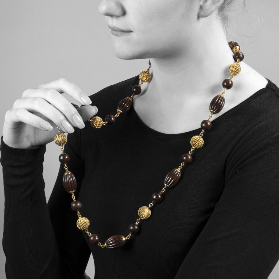 An eighteen carat yellow gold longchain made of beads carved from snakewood and of twisted gold wire. Signed Van Cleef & Arpels, Paris, made ca 1970.  