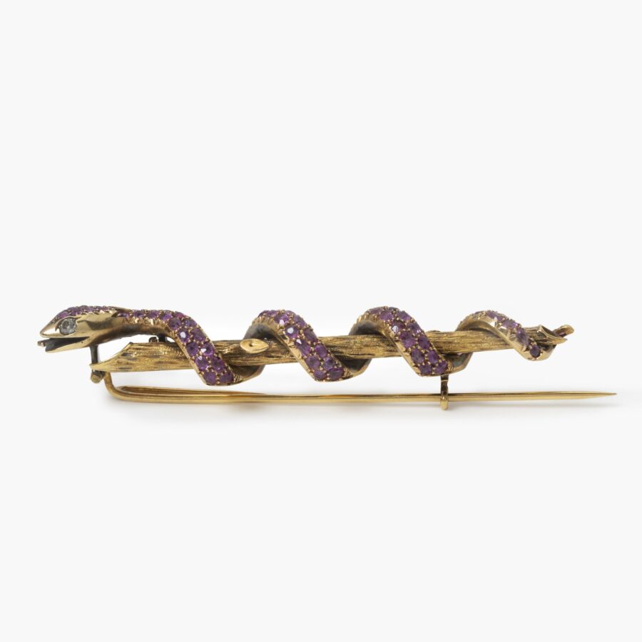An eighteen carat yellow gold brooch designed as a snake that wraps itself around a branch, the body fully pavé set with facetted rubies and two diamonds for eyes, the branch organically etched. Made in the Netherlands, ca 1890.