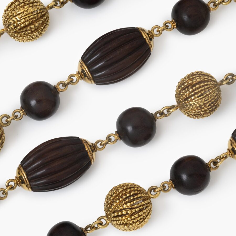 An eighteen carat yellow gold longchain made of beads carved from snakewood and of twisted gold wire. Signed Van Cleef & Arpels, Paris, made ca 1970.  