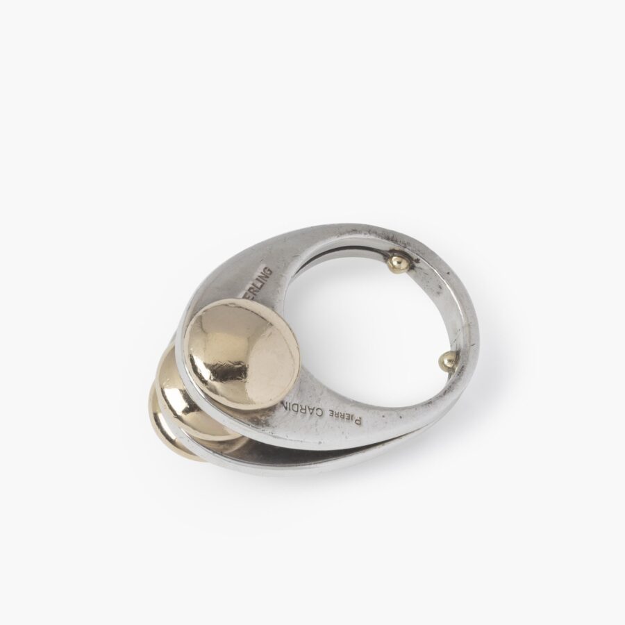 A sterling silver ring with two double convex fourteen carat yellow gold buttons. Signed Pierre Cardin, made ca 1965.