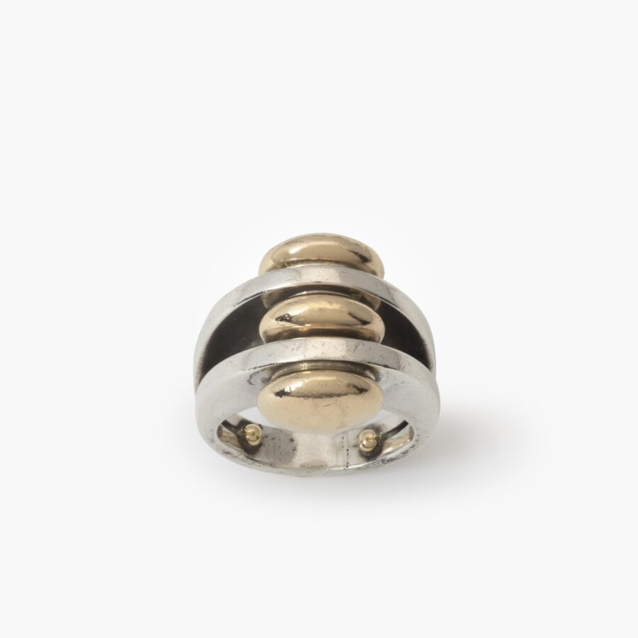 A sterling silver ring with two double convex fourteen carat yellow gold buttons. Signed Pierre Cardin, made ca 1965.
