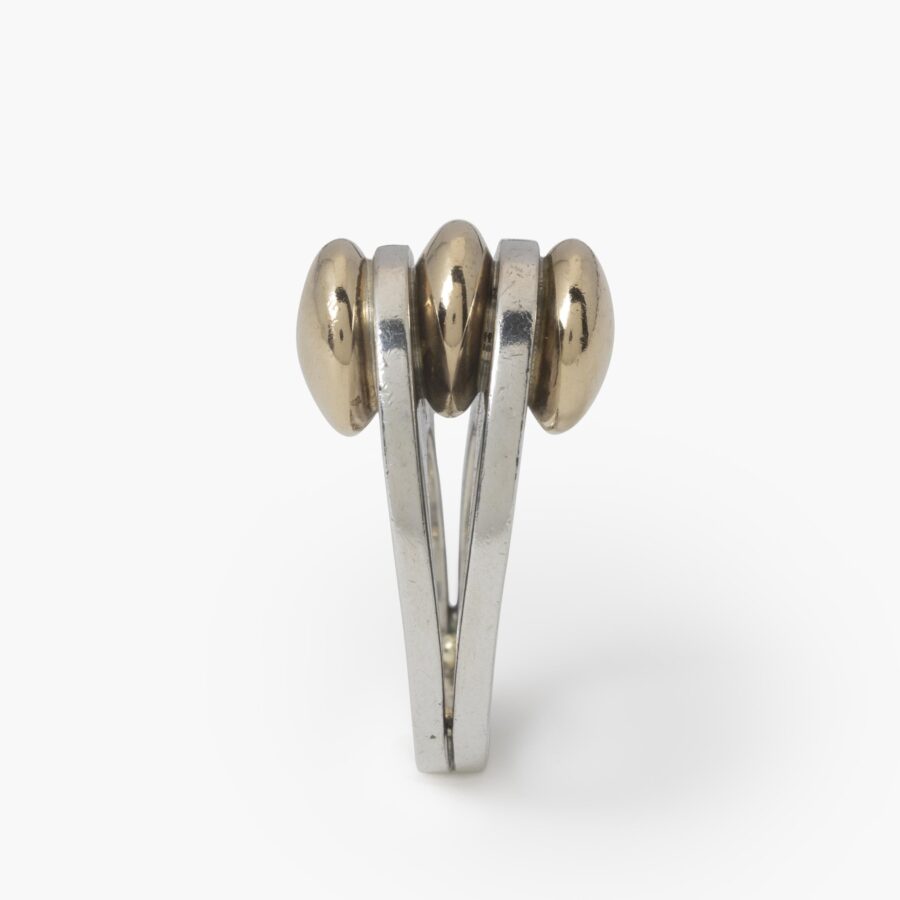 A sterling silver ring with two double convex fourteen carat yellow gold buttons. Signed Pierre Cardin, made ca 1965.