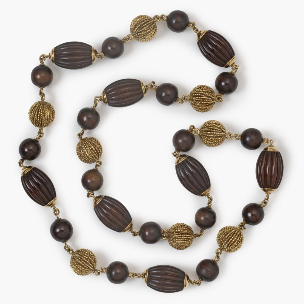 An eighteen carat yellow gold longchain made of beads carved from snakewood and of twisted gold wire. Signed Van Cleef & Arpels, Paris, made ca 1970.  