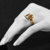 A fourteen carat yellow gold kinetic ring designed as two rotating open squares, each with one diamond. Signed N. Teufel, USA, dated 1972.