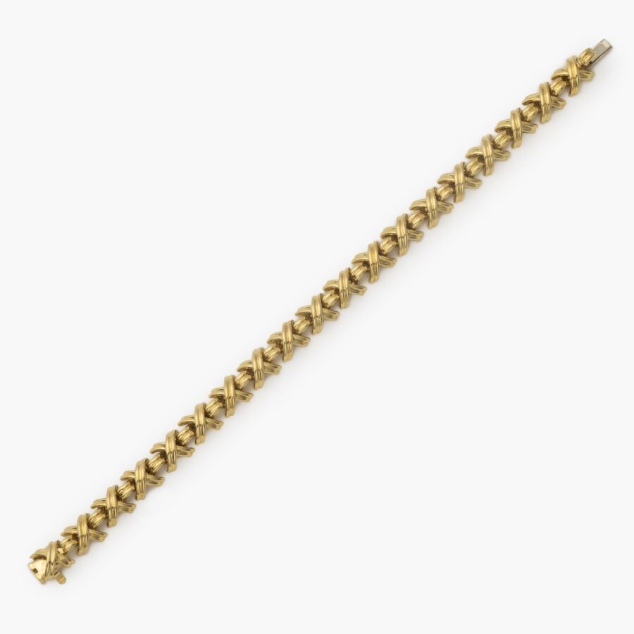 An eightteen carat yellow gold bracelet “Signature X” comprising nineteen x-shaped links, interconnected by bridge-shaped links, with box clasp with safety guard. After a design by Jean Schlumberger. Signed Tiffany & Co., USA.