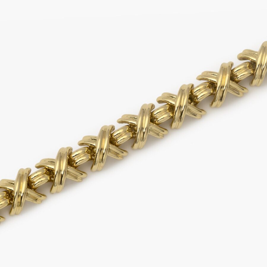 An eightteen carat yellow gold bracelet “Signature X” comprising nineteen x-shaped links, interconnected by bridge-shaped links, with box clasp with safety guard. After a design by Jean Schlumberger. Signed Tiffany & Co., USA.