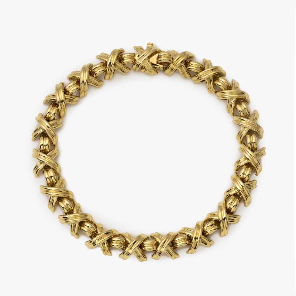 An eightteen carat yellow gold bracelet “Signature X” comprising nineteen x-shaped links, interconnected by bridge-shaped links, with box clasp with safety guard. After a design by Jean Schlumberger. Signed Tiffany & Co., USA.