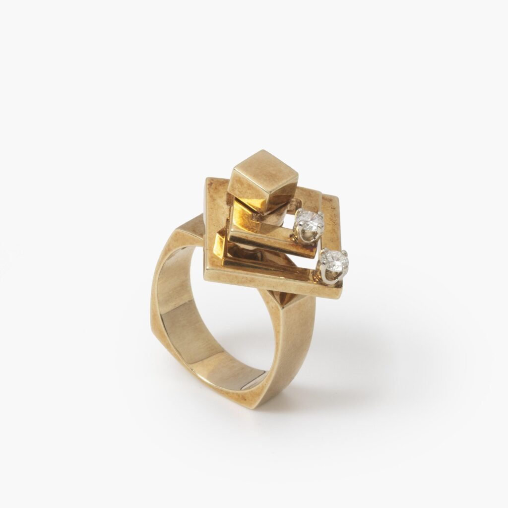A fourteen carat yellow gold kinetic ring designed as two rotating open squares, each with one diamond. Signed N. Teufel, USA, dated 1972.