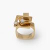 A fourteen carat yellow gold kinetic ring designed as two rotating open squares, each with one diamond. Signed N. Teufel, USA, dated 1972.