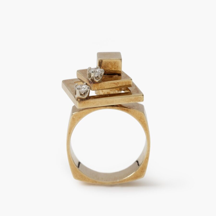 A fourteen carat yellow gold kinetic ring designed as two rotating open squares, each with one diamond. Signed N. Teufel, USA, dated 1972.
