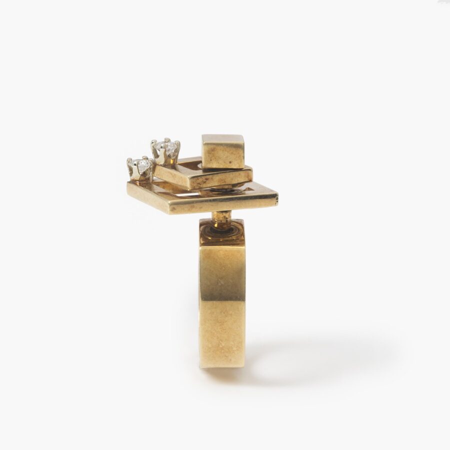 A fourteen carat yellow gold kinetic ring designed as two rotating open squares, each with one diamond. Signed N. Teufel, USA, dated 1972.