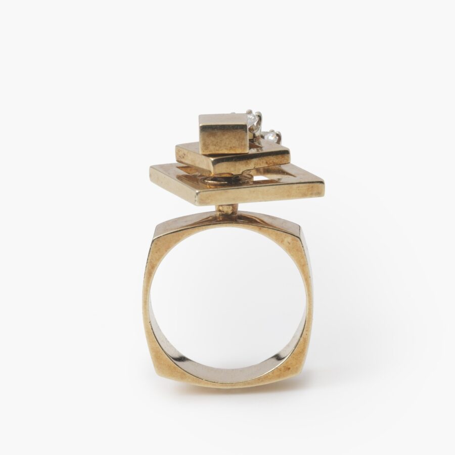 A fourteen carat yellow gold kinetic ring designed as two rotating open squares, each with one diamond. Signed N. Teufel, USA, dated 1972.