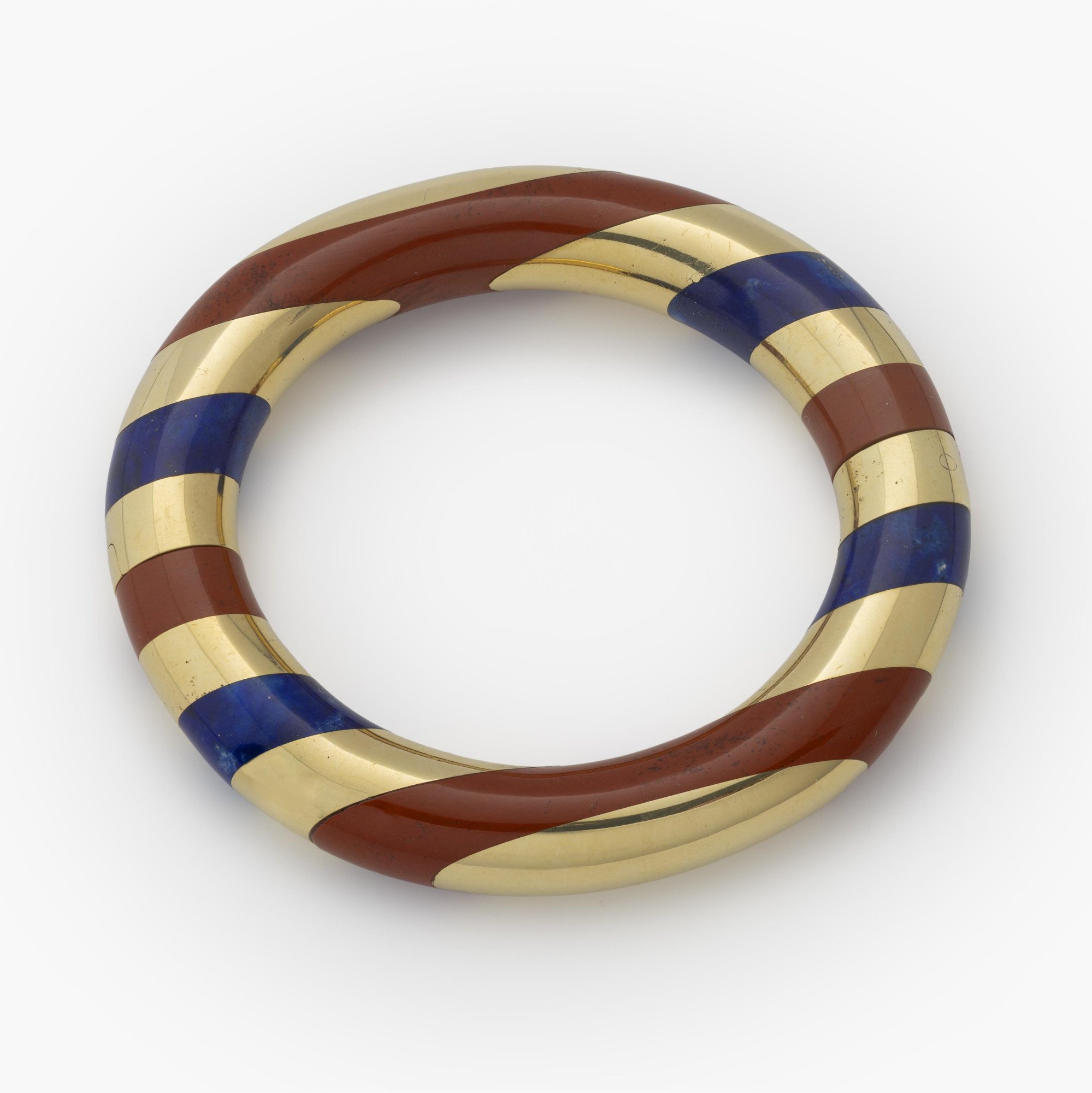 An eighteen-karat yellow gold rigid bracelet with bands of red jasper and lapis lazuli. Signed Tiffany & Co., made circa 1977. Designed by Angela Cummings.