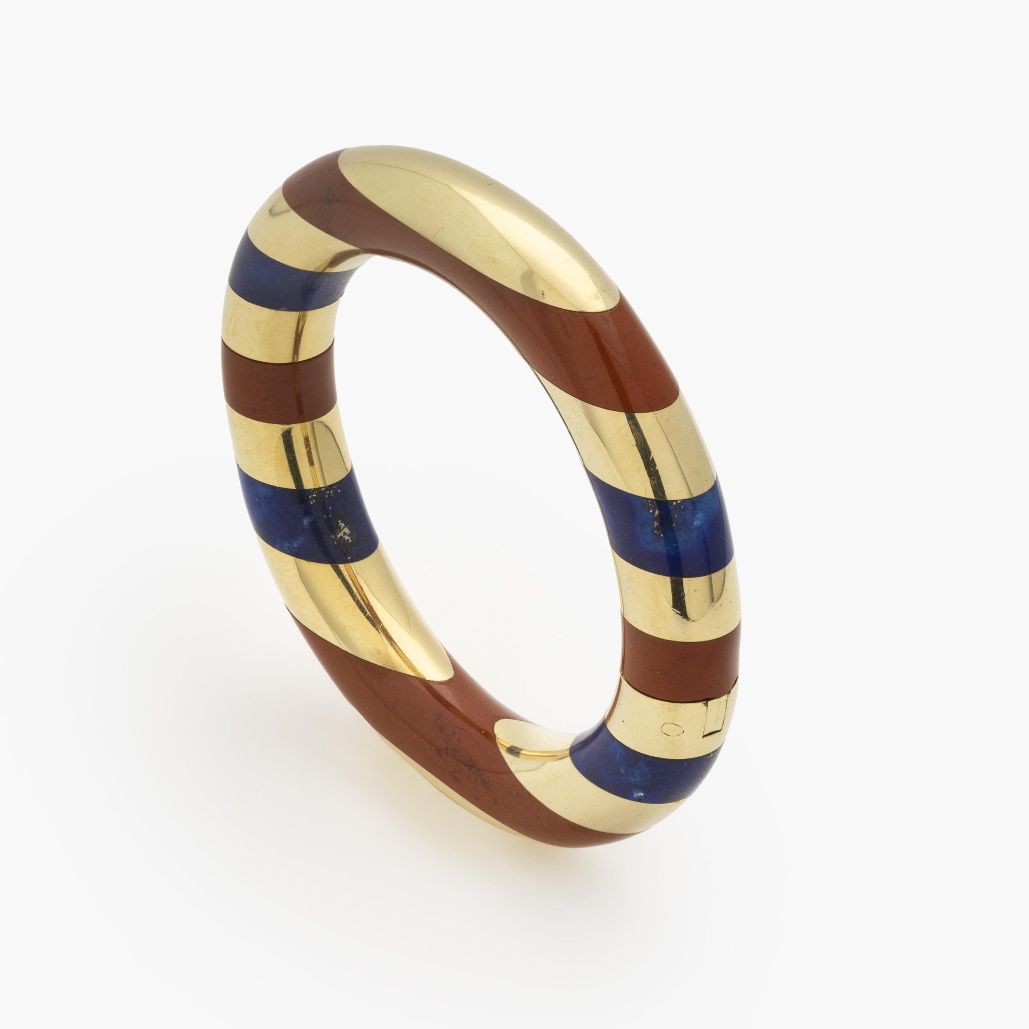 An eighteen-karat yellow gold rigid bracelet with bands of red jasper and lapis lazuli. Signed Tiffany & Co., made circa 1977. Designed by Angela Cummings.