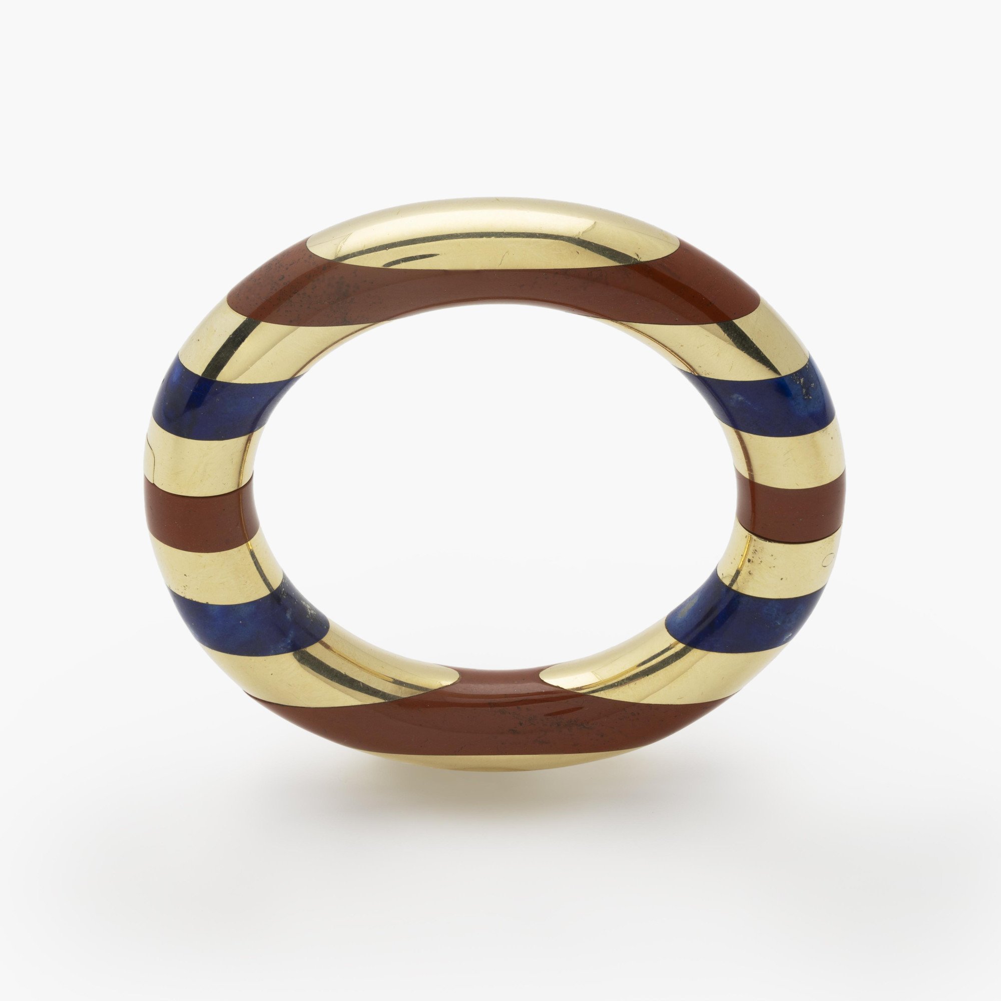 An eighteen-karat yellow gold rigid bracelet with bands of red jasper and lapis lazuli. Signed Tiffany & Co., made circa 1977. Designed by Angela Cummings.