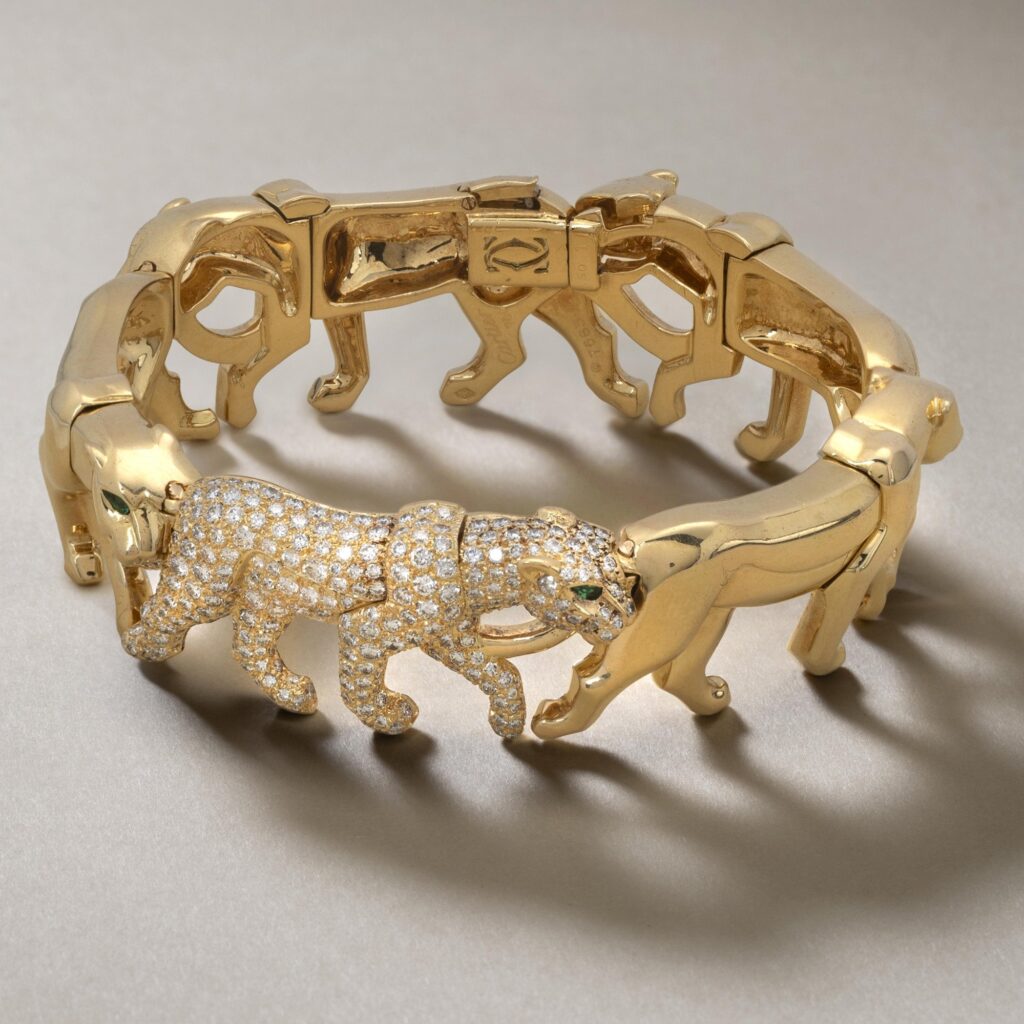 An eighteen carat yellow gold bracelet, designed as a row of five walking panthers, one of them set with diamonds. Signed Cartier, made in Paris.
