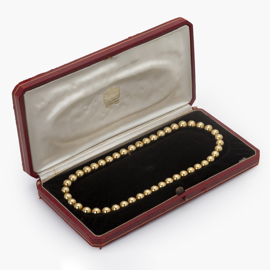 An eighteen carat yellow gold necklace made of strung beads. Signed Cartier Paris, made ca 1960. With original box.