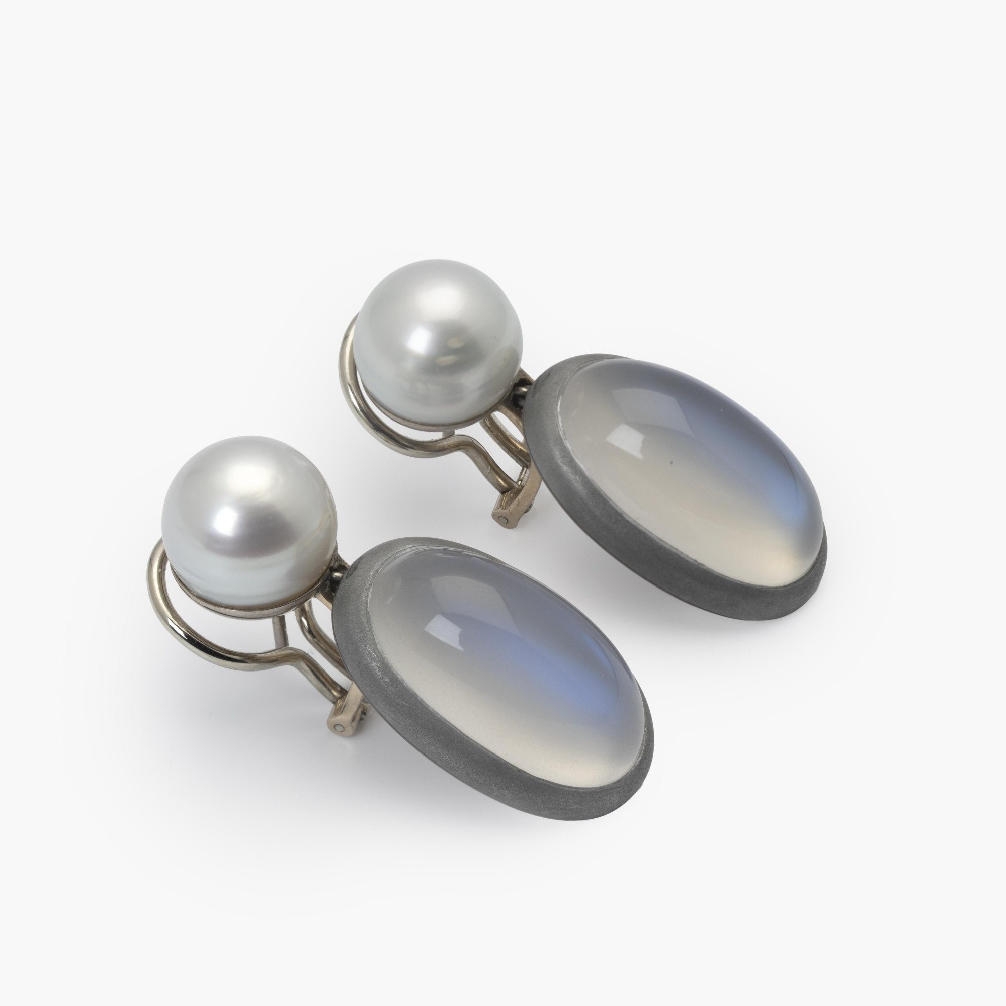 A pair of eighteen-carat white gold earrings, set with a South Sea pearl and a moonstone in aluminium. Signed Hemmerle, made in Munich. With original pouch.