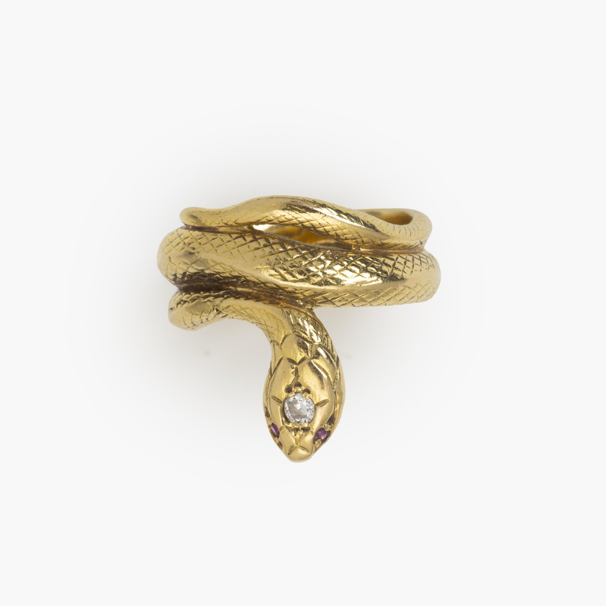 An eighteen-carat yellow gold ring designed as a snake; the head set with one brilliant-cut diamond and two rubies as eyes. Made ca 1960.