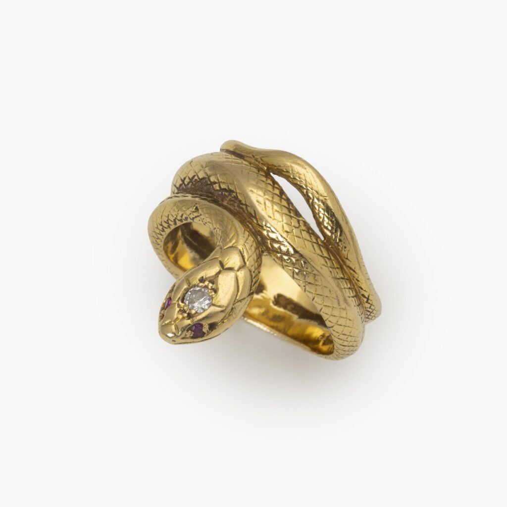 An eighteen-carat yellow gold ring designed as a snake; the head set with one brilliant-cut diamond and two rubies as eyes. Made ca 1960.