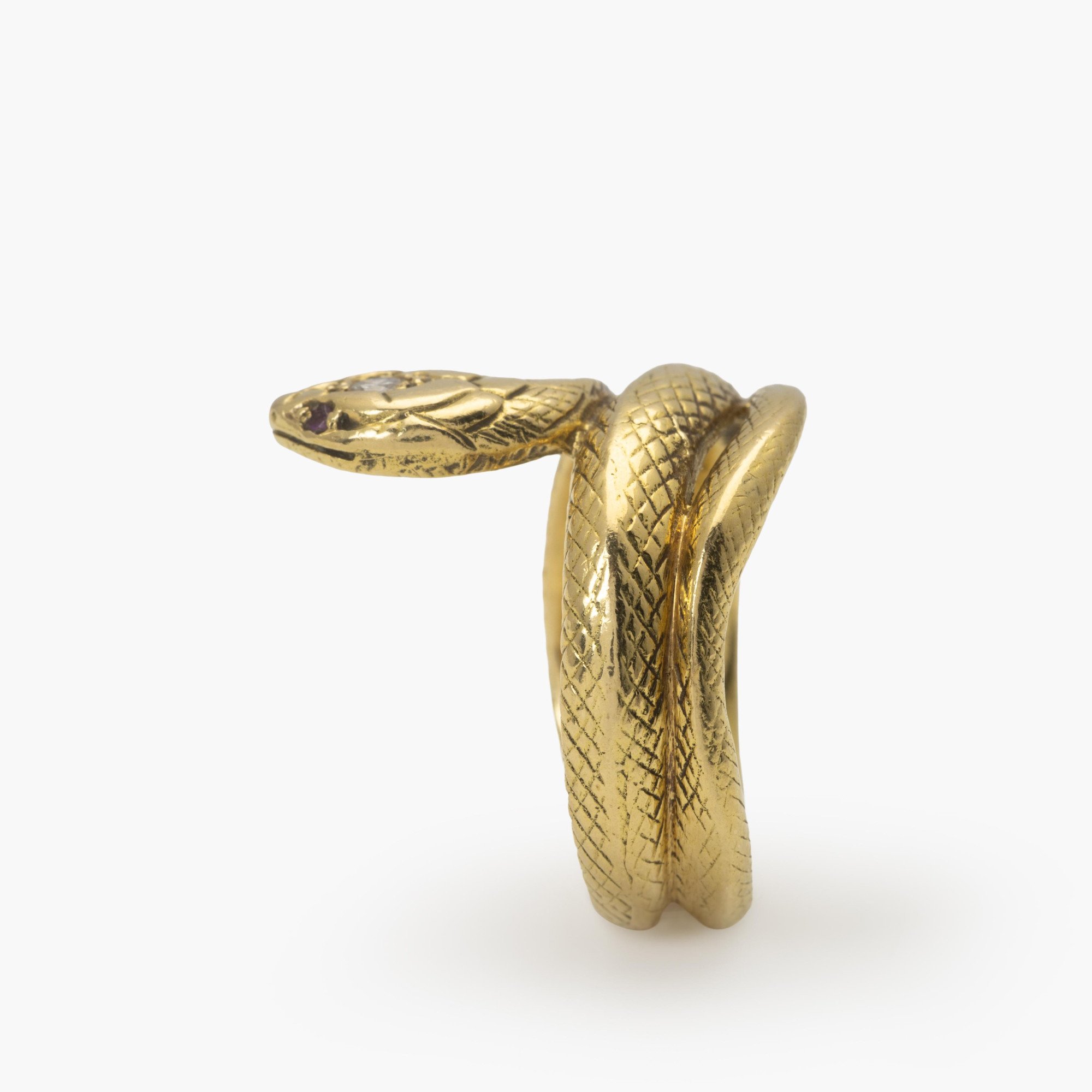 An eighteen-carat yellow gold ring designed as a snake; the head set with one brilliant-cut diamond and two rubies as eyes. Made ca 1960.