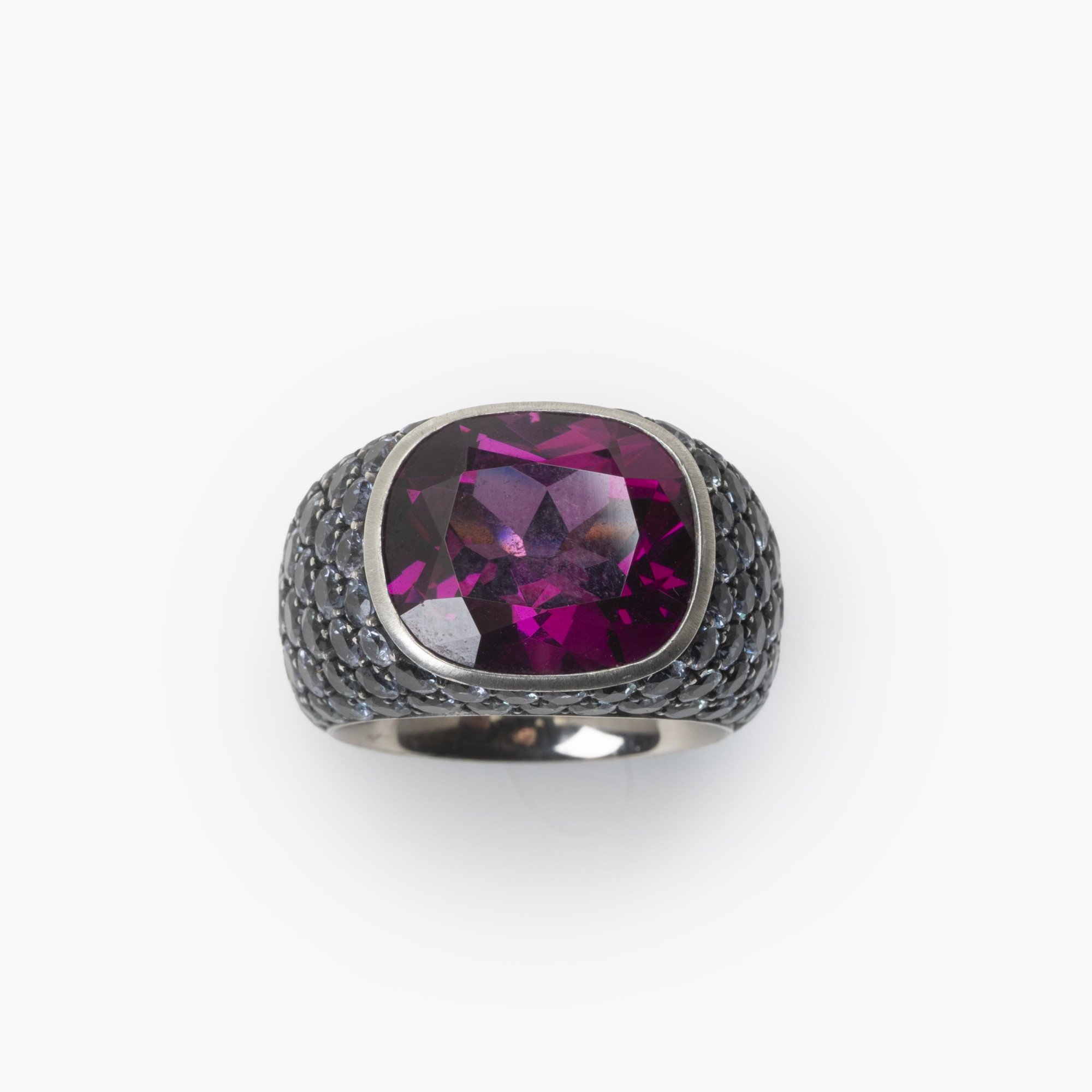 An eighteen-carat white gold and silver ring set with a very rare purple garnet and smaller purple-blue colour-change garnets. Hemmerle, Munich.