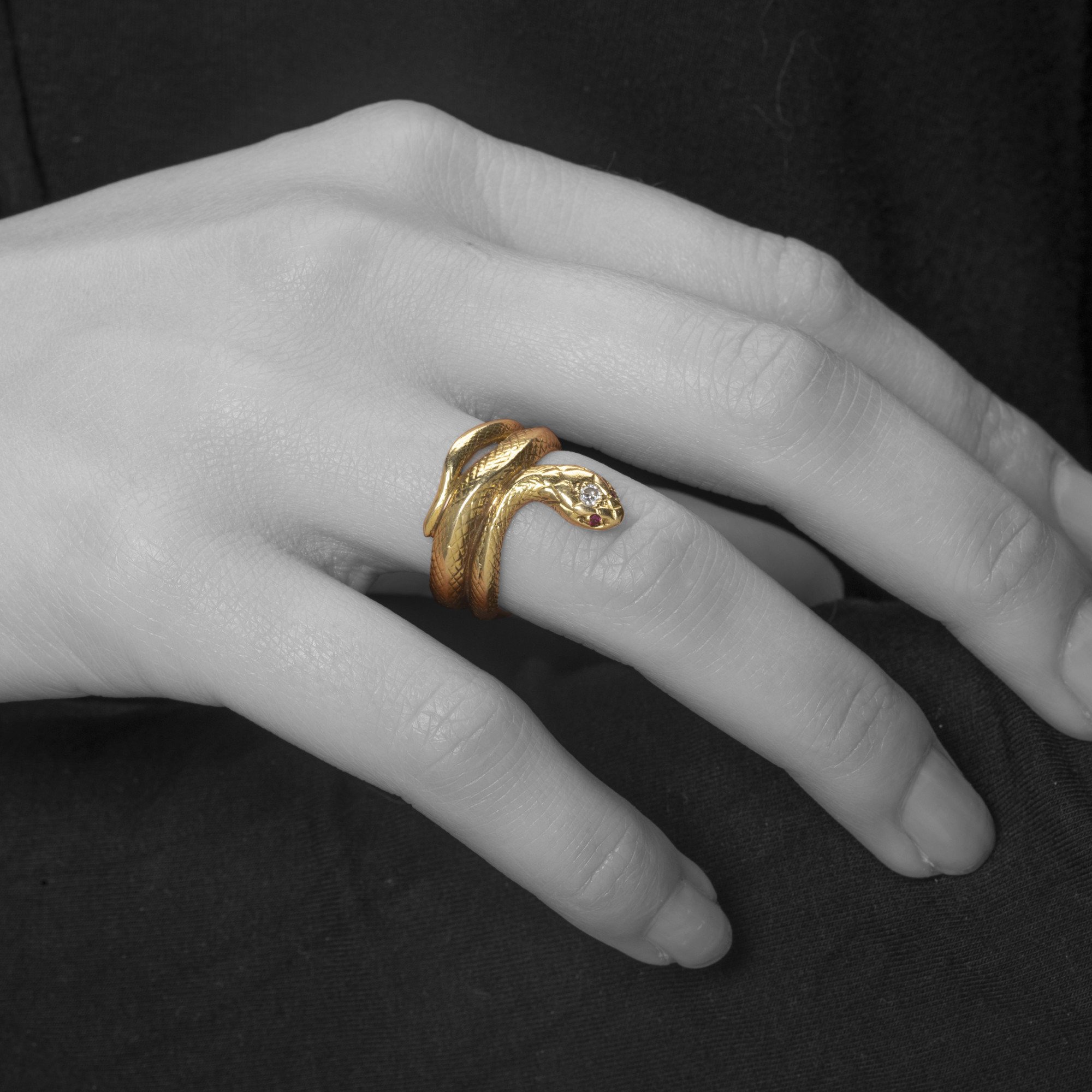 An eighteen-carat yellow gold ring designed as a snake; the head set with one brilliant-cut diamond and two rubies as eyes. Made ca 1960.