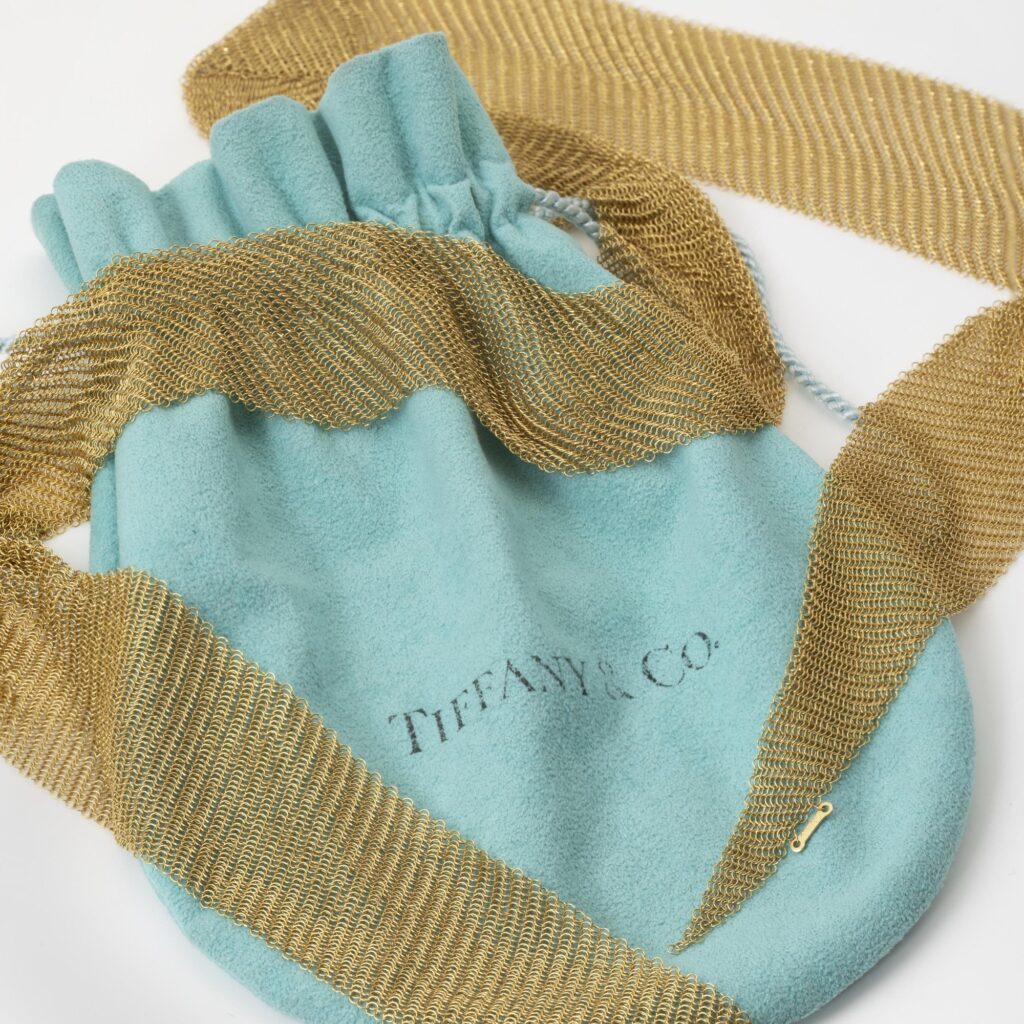 An eighteen carat yellow gold necklace designed as a scarf, signed Elsa Peretti for Tiffany & Co., made in the USA, ca 1980. With original pouch.