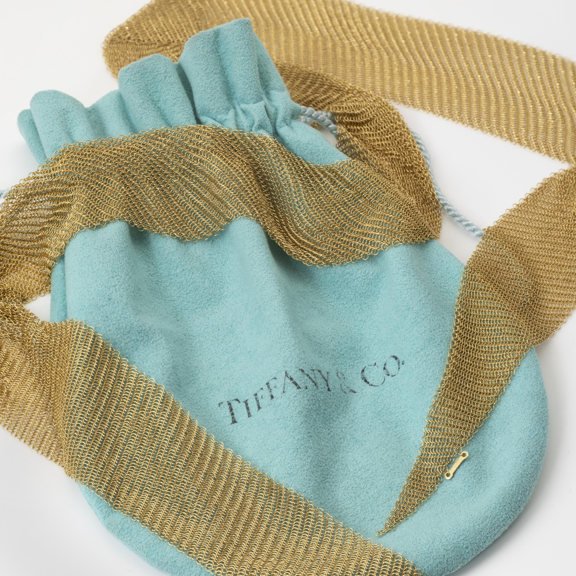 An eighteen carat yellow gold necklace designed as a scarf, signed Elsa Peretti for Tiffany & Co., made in the USA, ca 1980. With original pouch.
